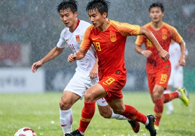 中国男足在世界杯预选赛中奋力拼搏的比赛画面，球员们在雨中激烈对抗拼抢每一球